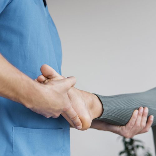 low-angle-male-osteopathic-therapist-checking-female-patient-s-leg-movement